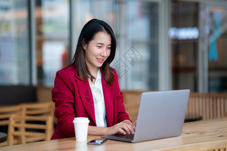 穿着红色西装的年轻女商人坐在咖啡馆酒吧的桌子旁图片