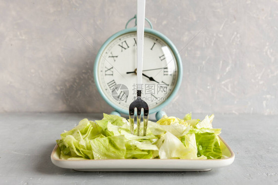 闹钟和绿色冰山生菜盘子间歇节食概念诱图片
