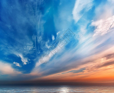 海边的粉色蓝日落天空中的蓝云图片