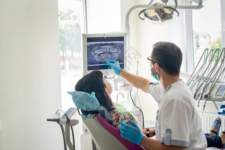 医生牙医在X光片上显示病人的牙齿图片