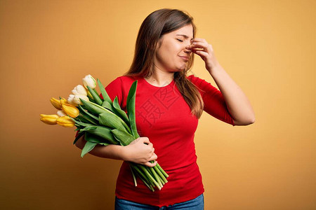 年轻的金发女人拿着浪漫的郁金香花束图片