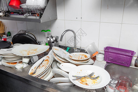 在专业餐厅厨房一堆不干净的白色板块陶器剩菜餐具自来水龙头砖墙上用脏盘子洗图片