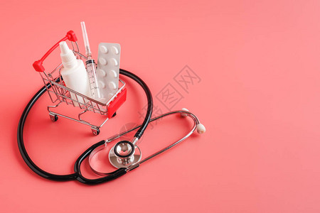 使用药丸注射器和瓶子的购物车听诊器放在粉红色背景的图片