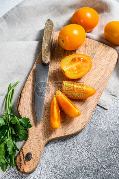 切割板上的生黄番茄切片白色背图片