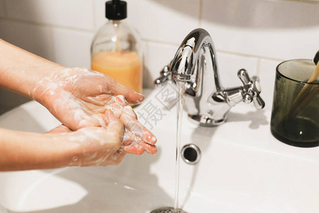 洗手在浴室流水的背景下用肥皂泡沫洗手揉搓手掌预防流感个人卫生清洁双手以防止背景图片