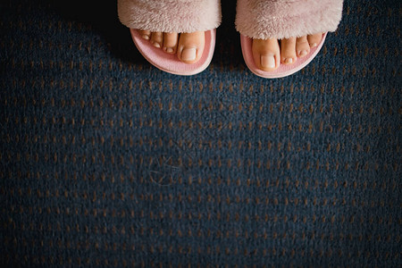 酒店室内效果图在深蓝色地毯背景上用粉红色毛绒拖鞋修脚的女腿背景