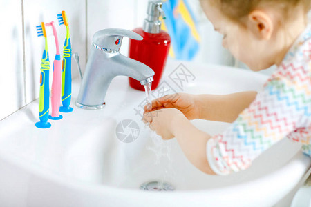 蹒跚学步的小女孩在浴室里用肥皂和水洗手的特写镜头关闭孩子清洁身体部位早上的卫生习惯健康的孩子在图片