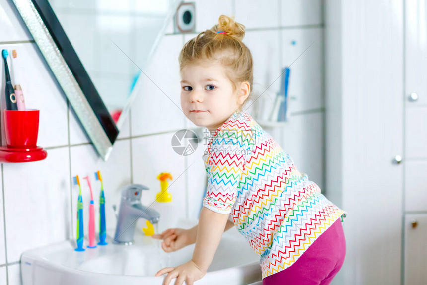 可爱的蹒跚学步的小女孩在浴室里用肥皂和水洗手可爱的孩子学习清洁身体部位疾病期间的卫生常规措施在家或图片