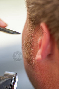 理发师在专业美发沙龙或理发店用理发器或理发器剃掉老人的胡须和胡须图片