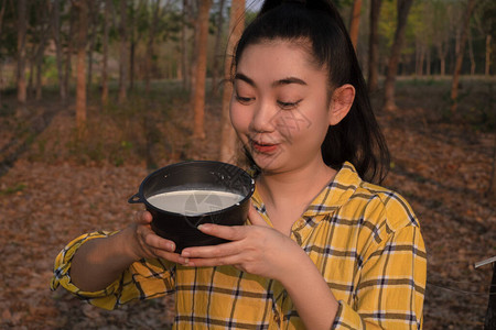 一位年轻的海区女青年肖像园艺员望着一整杯树的原橡胶脂奶图片