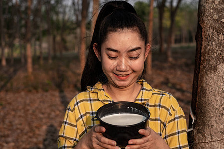 一位年轻的海区女青年肖像园艺员望着一整杯树的原橡胶脂奶图片