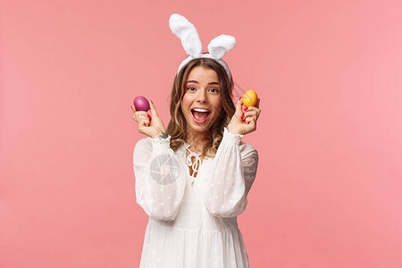 穿着兔子耳朵和白色派对礼服庆祝复活节的兴奋迷人的年轻女子的肖像图片