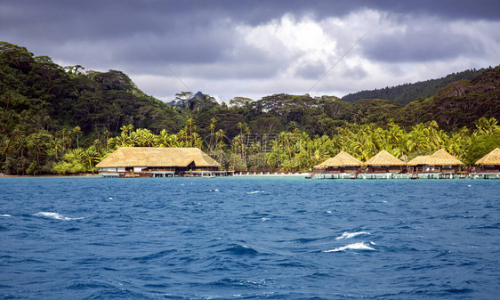 豪华水上茅草屋顶平房度假村位于法属波利尼西亚波拉岛日出光线下图片