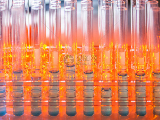 在温暖的橙色背景上含有蓝色液体的玻璃试管实验室科图片