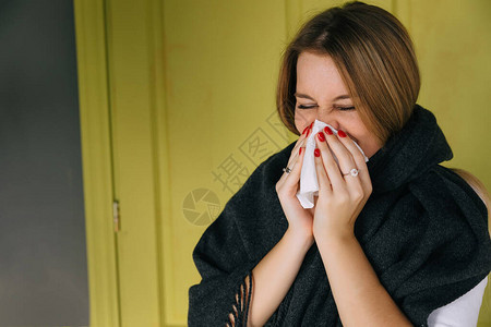 患有季节流感的生病的年轻女子用纸巾擤鼻涕图片