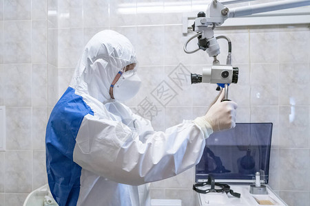 大流行期间身穿防护服的医生用医疗设备检查病人立体显微镜流行病概念图片