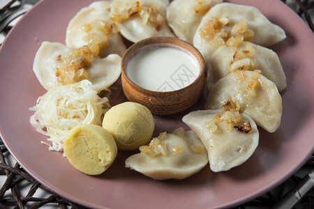 饺子汤圆含炖菜卷心菜和炸洋葱自制的土制传统乌克兰盘子蒸发背景