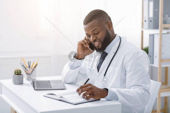 年轻非洲医生在现代诊所工作时通过电话与病人交谈图片