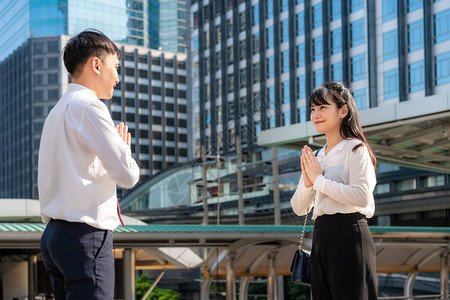 商人和女商人朋友在办公楼的字体中相遇他们没有用或握手打招呼图片