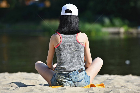 戴帽子的女孩坐在沙滩上图片