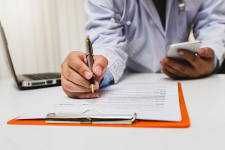 穿着长袍的医生用钢笔在病历上写字图片