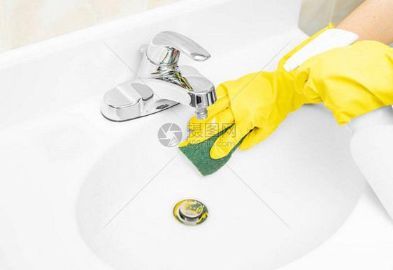 戴黄色橡胶手套的妇女正在用洗涤剂和海绵图片