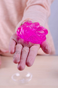 孩子手中的玩具史莱姆小女孩在玩明亮的粉红色伸展粘液全球流行的自制玩具图片