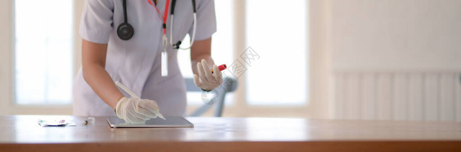 女医生站在检查室时在数字平板电脑上进行血液检测的图片