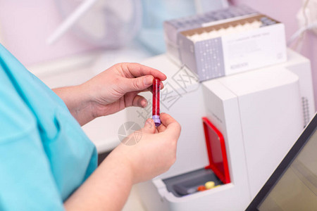 血液分析仪医学实验室的实验室助理手里拿着装有血液和血浆的试背景图片