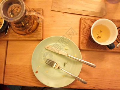在木制桌上吃完饭后剩菜盘子和碎屑图片