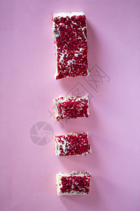 宝龙广场Torrone或牛轧糖棒与坚果和红色干浆果传统的意大利甜点靠近粉红色的背景甜可口背景