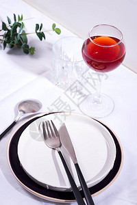 为节日餐桌服务的餐具和装饰品白色纺织品背景上有绿叶的盘子图片