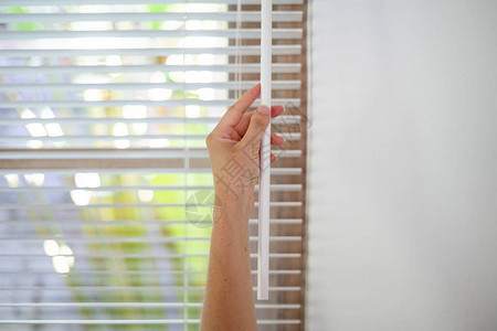 女在窗户上关闭现代白色百叶窗的剪影图片