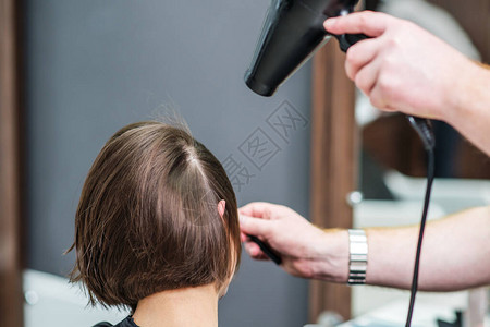 专业美发师正在美容院吹干女头发型师手臂的特写使女头发变干发图片