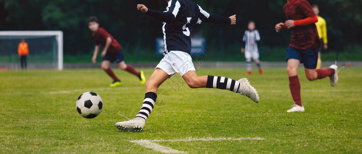 足球运动员在比赛中奔跑和踢球初级足球运动员参加足球锦标赛男生队之图片