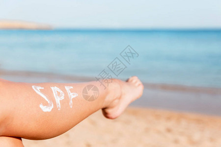 在海滩上用日霜做成的雌腿太阳保护因素的概图片
