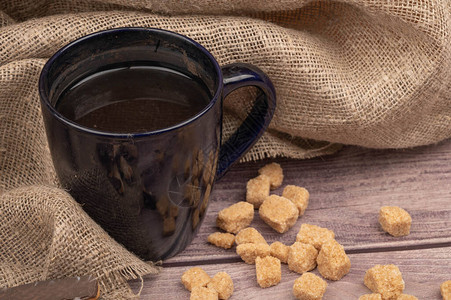 深蓝色陶瓷茶杯和一片棕色甘蔗糖背景粗糙图片