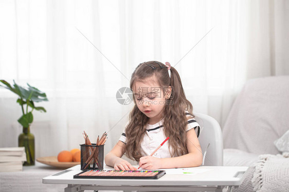 这个女孩正坐在桌旁做作业孩子在家学习在家上学图片