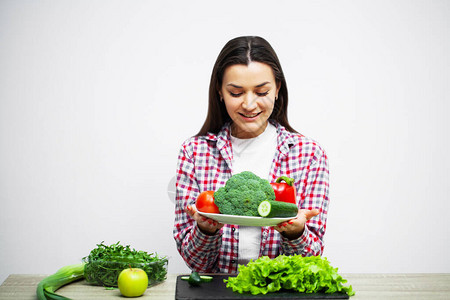 健康饮食和饮食女孩在背景白墙上持有蔬菜的概念b图片