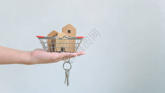 在篮子和家用钥匙链中手持木屋房地产投资和房屋抵押金融不动产概念图片