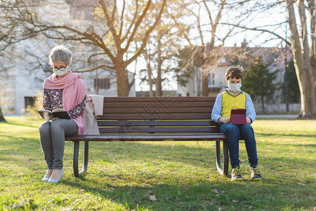 外祖母和孙子被坐在公园长椅上的社会图片
