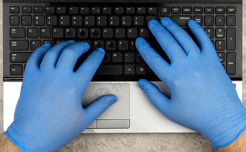 手戴着医用手套在键盘上在检疫冠状COVID19期间在线学习或工作远程工作防止流行病蔓图片