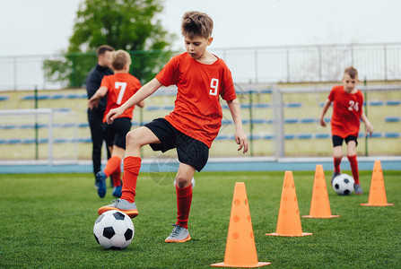 儿童足球队训练中的男孩子们用足球在户外练习在足球营为孩子们训练足球课小男孩提高运球技巧图片