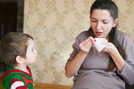 这个小男孩看着一个生病的怀孕母亲流鼻血的怀孕年轻妇女图片