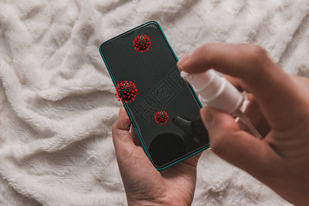 用防腐消毒剂喷雾液的人手擦拭智能手机屏幕上的电晕细菌细菌图片