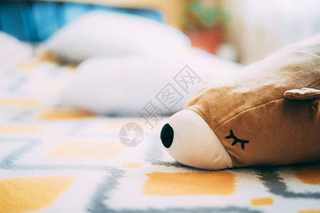 一个柔软蓬松的熊玩具躺在床上漂亮的黄色床罩上晴天慵懒的心情在家昏欲睡的状态待机模式儿童和成人玩具因为在家图片