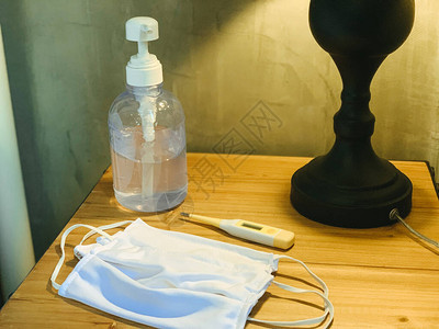 预防科罗纳的外科手术口罩洗手液凝胶和木制桌上温度计图片