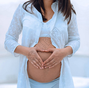 孕妇手牵在她的肚子上呈心形母概念图片