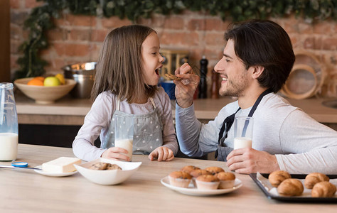 健康早餐照顾年轻父亲喂小女儿用自制饼干和在厨房复印空间一起喝牛图片
