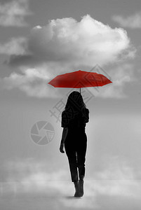 带雨伞的女孩在梦幻般的背景下的剪影带铅色天空的红色雨图片